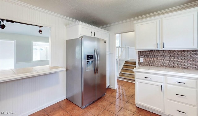 kitchen featuring tasteful backsplash, ornamental molding, stainless steel fridge, and white cabinets