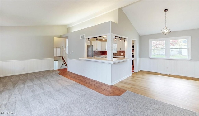 kitchen featuring vaulted ceiling, wainscoting, carpet floors, and freestanding refrigerator