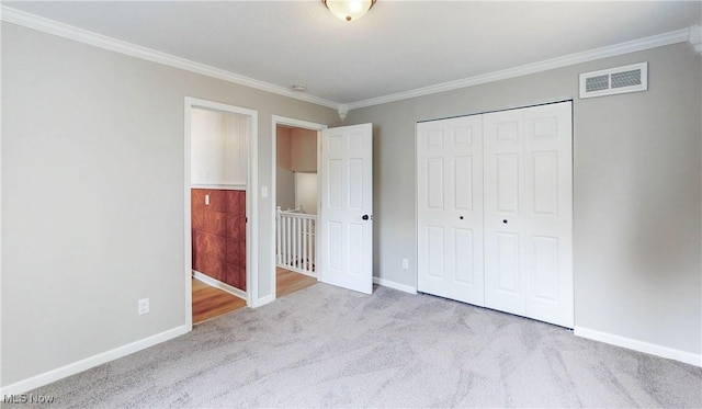 unfurnished bedroom featuring carpet floors, a closet, ornamental molding, baseboards, and visible vents