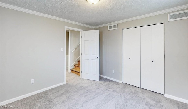 unfurnished bedroom featuring a closet, visible vents, a textured ceiling, and carpet floors
