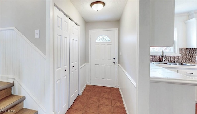 doorway to outside with tile patterned floors, wainscoting, stairs, and a sink