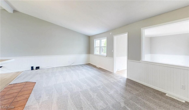 spare room with visible vents, wainscoting, vaulted ceiling with beams, and carpet