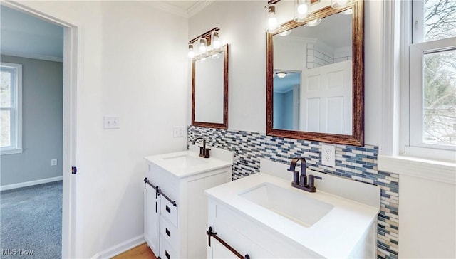 bathroom with crown molding, two vanities, a sink, and decorative backsplash