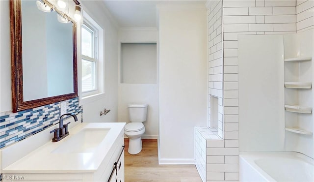 bathroom with wood finished floors, ornamental molding, backsplash, toilet, and vanity