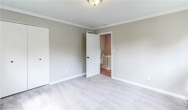 unfurnished bedroom featuring baseboards, crown molding, a closet, and carpet