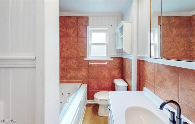 full bathroom with tile walls, toilet, crown molding, and a whirlpool tub