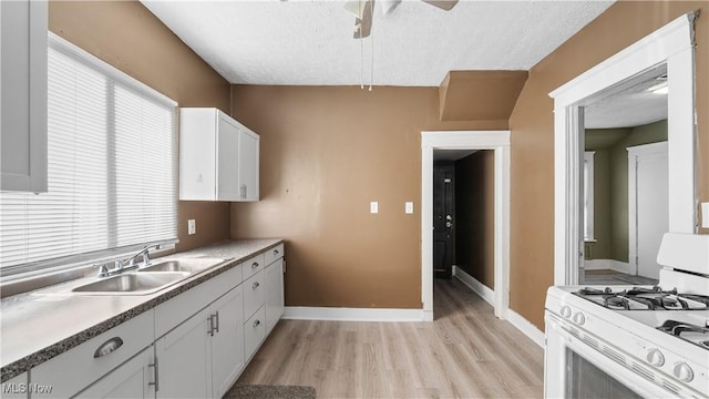 636-638 Fern St, Akron, OH 44307 - kitchen with white range with gas cooktop, a sink, light wood-type flooring, baseboards, and a textured ceiling