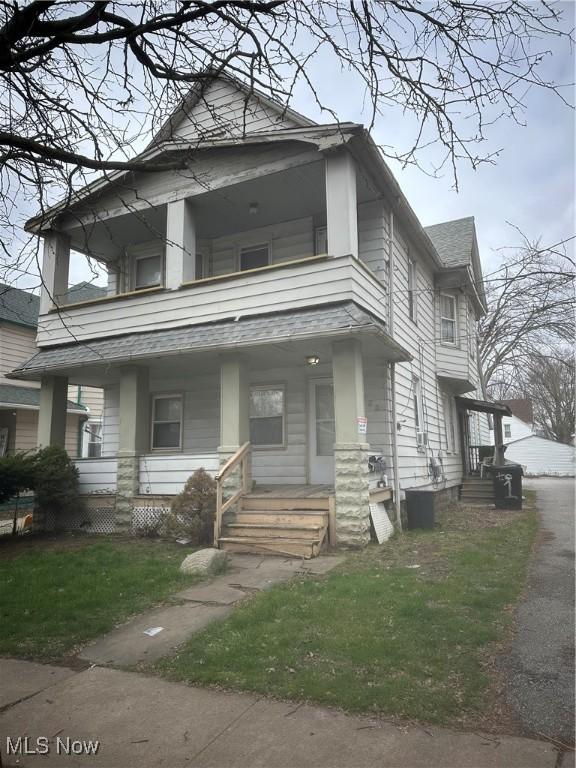 view of front facade featuring a porch, a front lawn, a shingled roof, and a balcony