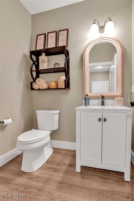 4591 Boulder Ln, Lorain, OH 44053 - half bath featuring baseboards, vanity, toilet, and wood finished floors