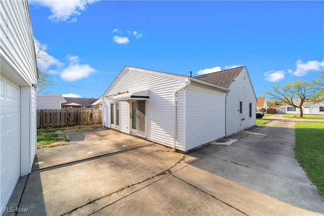 rear view of property featuring a patio, fence, and roof with shingles