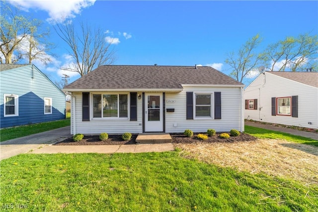 view of front of property with a front yard and a shingled roof