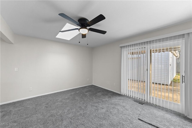 carpeted spare room featuring baseboards, visible vents, a skylight, and a ceiling fan