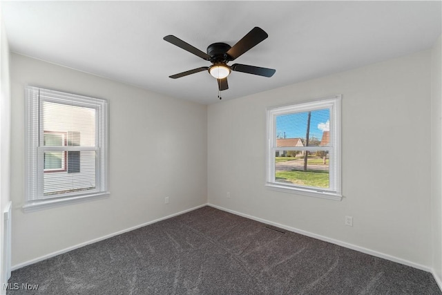 unfurnished room with dark carpet, ceiling fan, visible vents, and baseboards