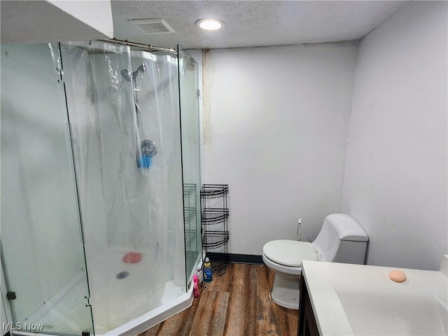 bathroom with a shower stall, visible vents, toilet, wood finished floors, and vanity