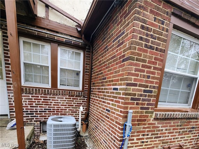 view of side of property with cooling unit and brick siding