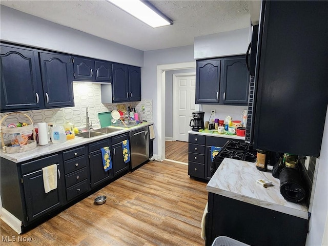 kitchen featuring tasteful backsplash, stainless steel dishwasher, light wood-style flooring, light countertops, and a sink