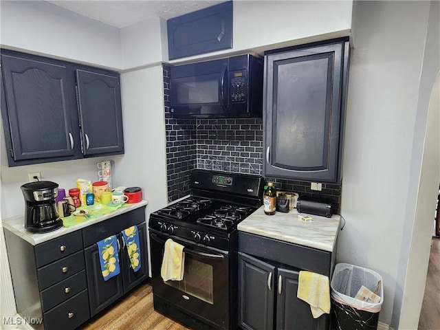 kitchen with black appliances, light countertops, tasteful backsplash, and light wood-type flooring