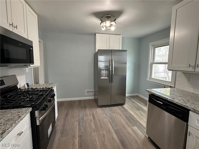 kitchen featuring baseboards, tasteful backsplash, stainless steel appliances, and light wood-type flooring