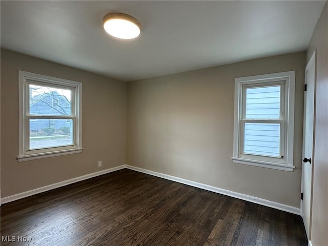 empty room with baseboards and dark wood-type flooring