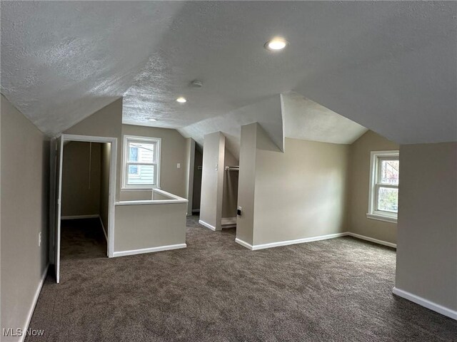 bonus room featuring recessed lighting, baseboards, dark carpet, a textured ceiling, and lofted ceiling