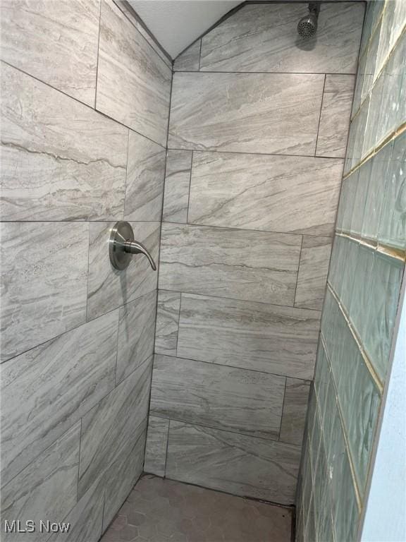 bathroom featuring a tile shower and vaulted ceiling