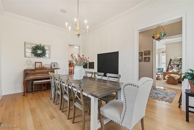 dining space featuring ornamental molding, baseboards, a chandelier, and light wood-style floors