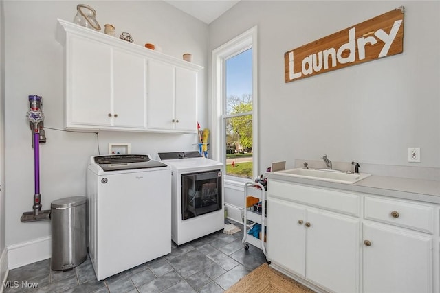 clothes washing area featuring washer and clothes dryer, cabinet space, baseboards, and a sink