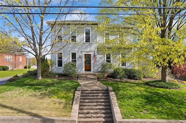 colonial-style house featuring a front lawn