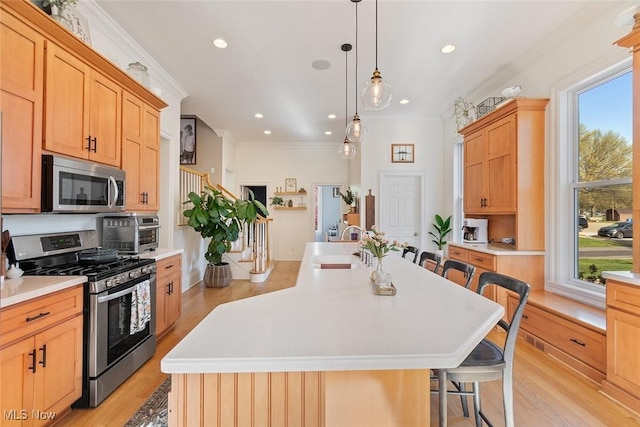 kitchen with light wood-style flooring, a sink, a breakfast bar, stainless steel appliances, and light countertops
