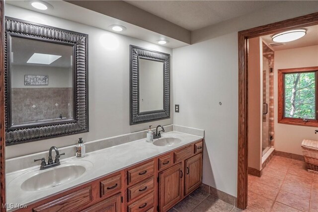 bathroom with tile patterned floors, a shower stall, double vanity, and a sink