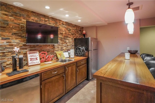 kitchen featuring hanging light fixtures, freestanding refrigerator, butcher block counters, dishwasher, and a sink