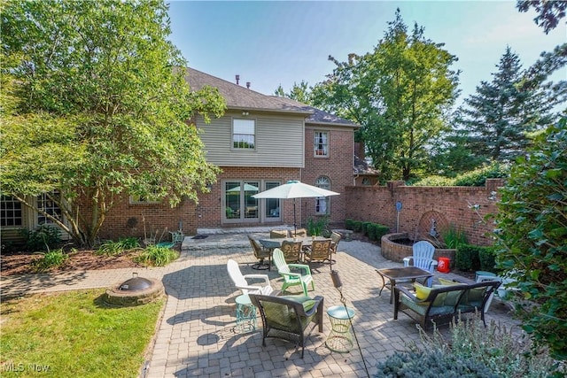 rear view of house featuring fence, an outdoor fire pit, a patio, and brick siding