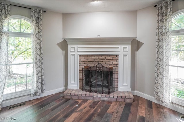 unfurnished living room featuring a fireplace, wood finished floors, visible vents, and baseboards