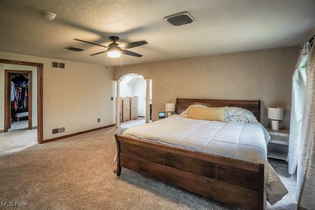 bedroom with visible vents, arched walkways, light carpet, and a ceiling fan