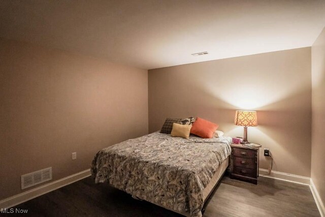 bedroom with baseboards, visible vents, and wood finished floors