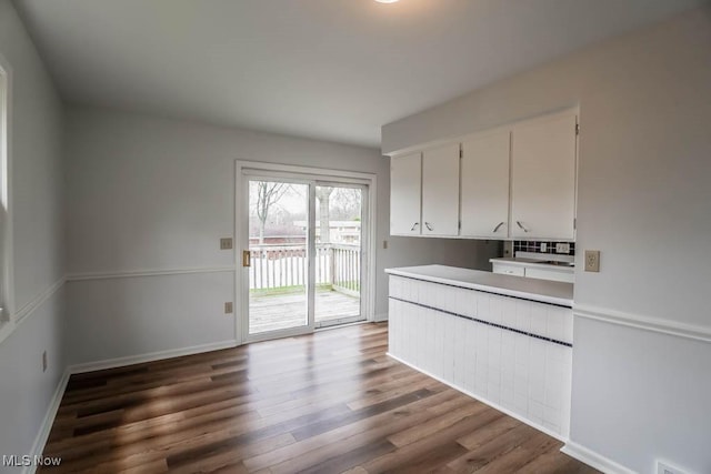 kitchen featuring wood finished floors, light countertops, white cabinets, and baseboards