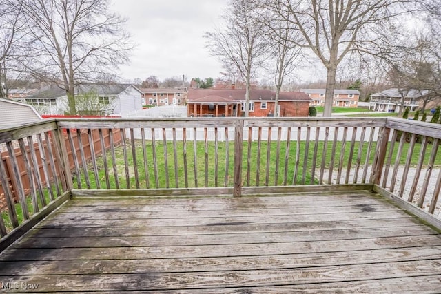 wooden terrace with a fenced backyard, a residential view, and a lawn