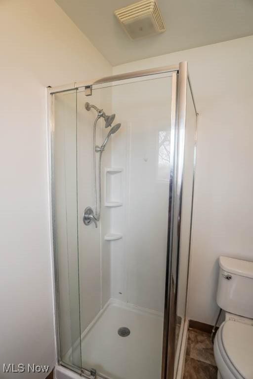 bathroom featuring toilet, a stall shower, and visible vents