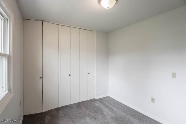unfurnished bedroom with two closets, carpet floors, and baseboards