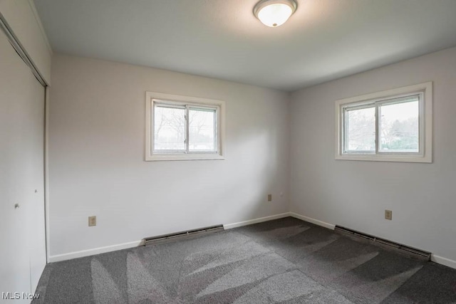 empty room with baseboards, visible vents, a healthy amount of sunlight, and a baseboard heating unit