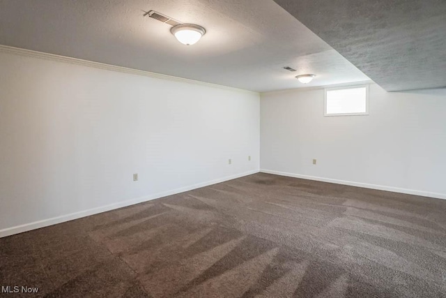 below grade area with baseboards, visible vents, a textured ceiling, and carpet flooring
