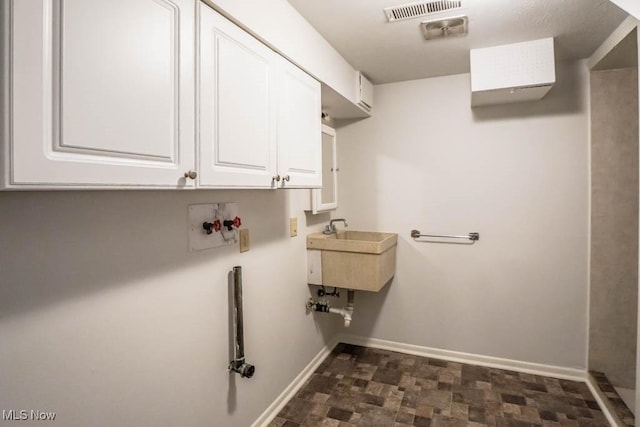 clothes washing area featuring baseboards, visible vents, cabinet space, and a sink