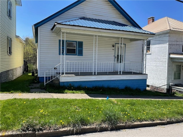 bungalow with covered porch, a front lawn, and metal roof