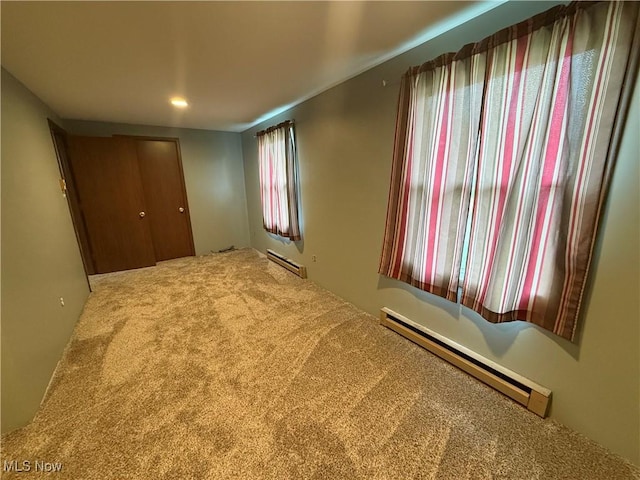 unfurnished bedroom featuring a closet, carpet floors, and a baseboard radiator
