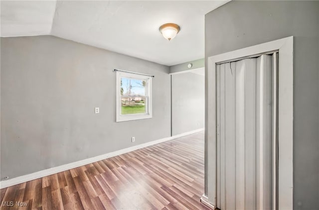 interior space with baseboards, wood finished floors, and lofted ceiling