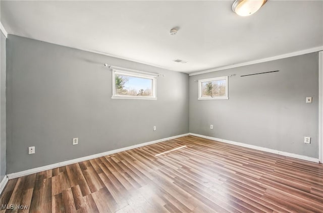 unfurnished room featuring visible vents, wood finished floors, and baseboards