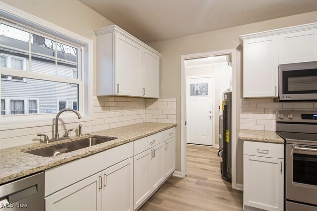 kitchen with white cabinetry, light wood-type flooring, appliances with stainless steel finishes, and a sink