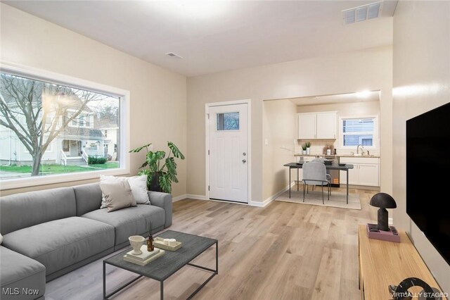 living area featuring visible vents, baseboards, a wealth of natural light, and light wood-type flooring