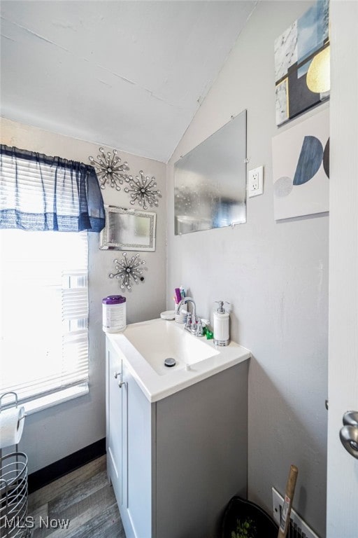 bathroom featuring wood finished floors, a healthy amount of sunlight, vanity, and vaulted ceiling