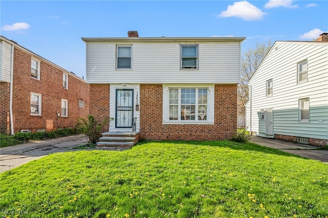 view of front of home with a chimney, brick siding, and a front lawn